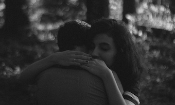 Black and white phone of a woman hugging a man. 